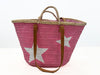 Rear view of pink woven beach basket with leather straps and pink textile inlet on white background.