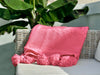 Cotton blanket in pink with pompoms displayed on a sofa — VVC SHOP SITIA Black Friday sale