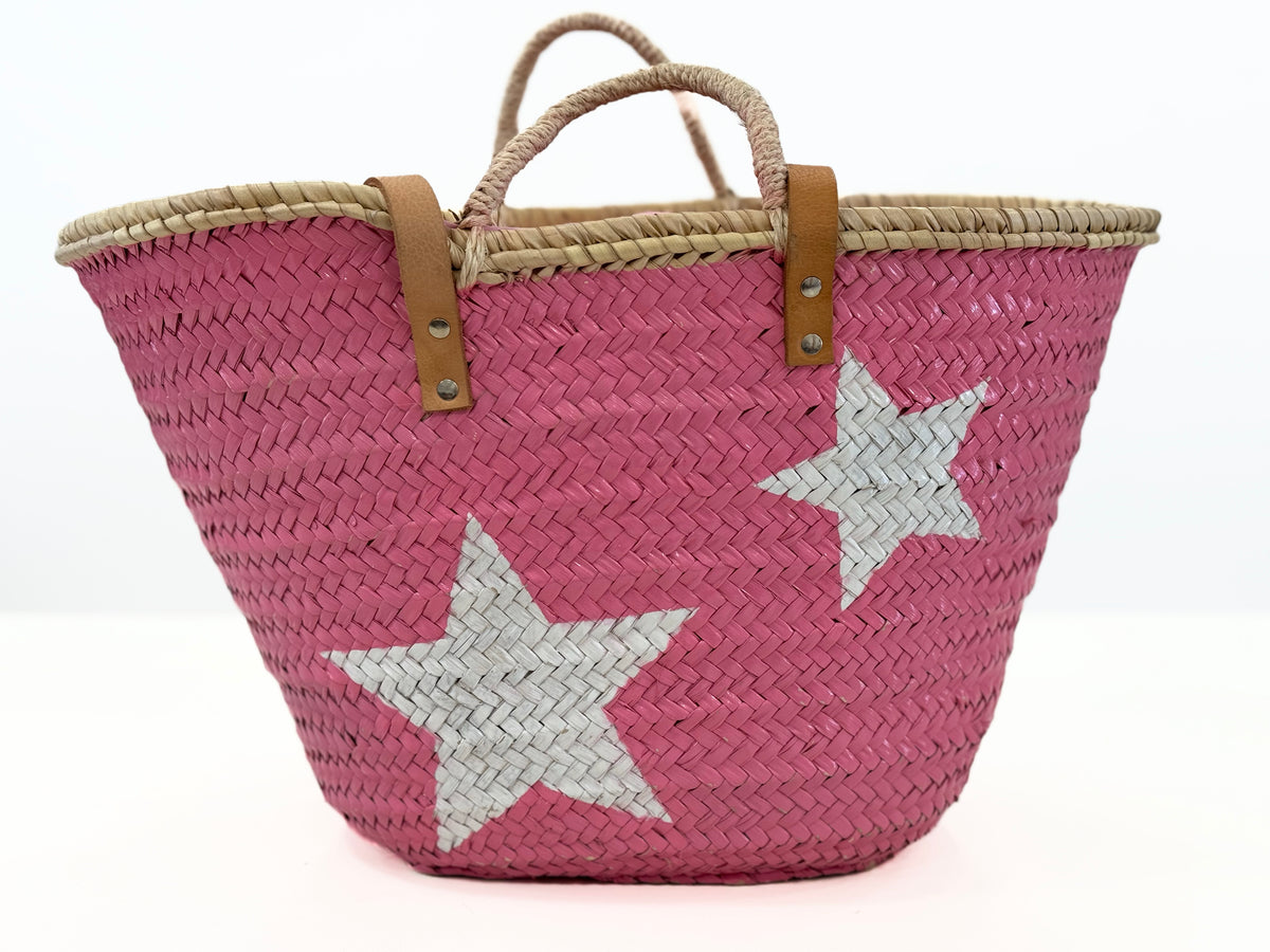 Backside view of pink handmade palm leaf basket with woven texture and natural rim on white background.