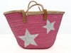Backside view of pink handmade palm leaf basket with woven texture and natural rim on white background.