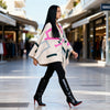 Woman walking on a street wearing a colorful poncho and black knee-high boots.