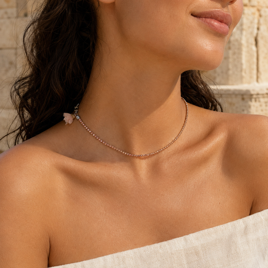 Woman wearing a rose-nude rhinestone necklace with blush textile flower, available at VVC Shop Sitia, Crete.