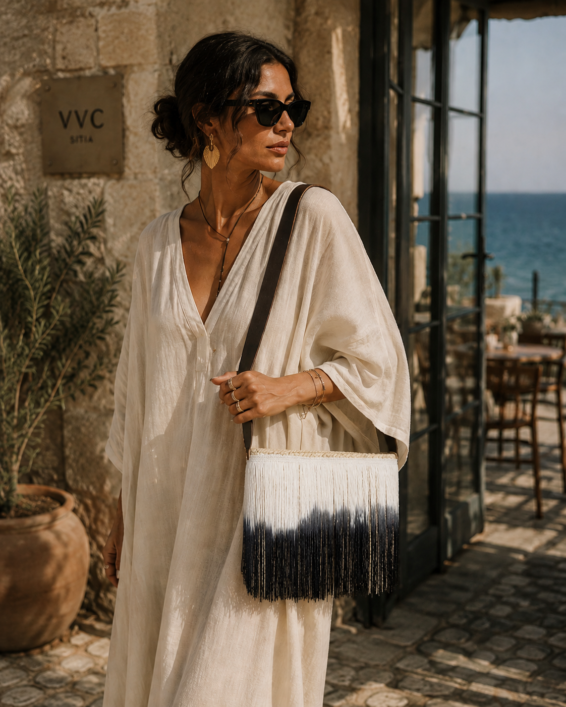 Small raffia fringe shoulder bag by VVC styled as a Mediterranean summer accessory with white boho resort outfit