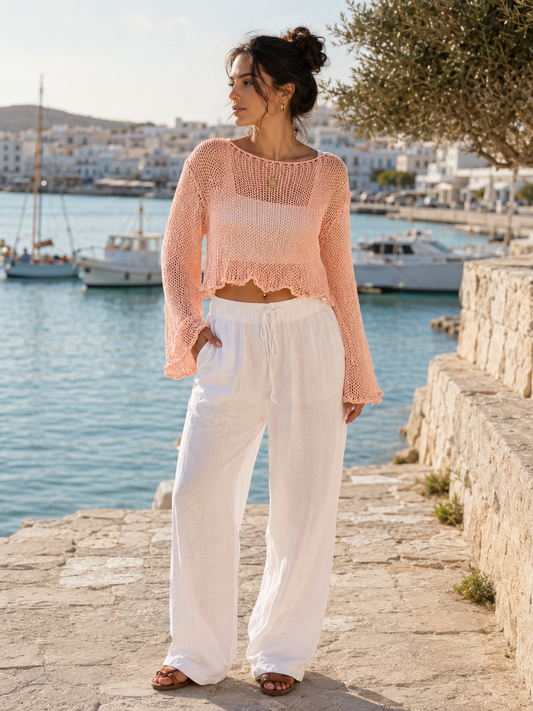Soft peach open-knit cropped summer top styled with white trousers by the harbour at VVC SHOP Sitia, Crete.