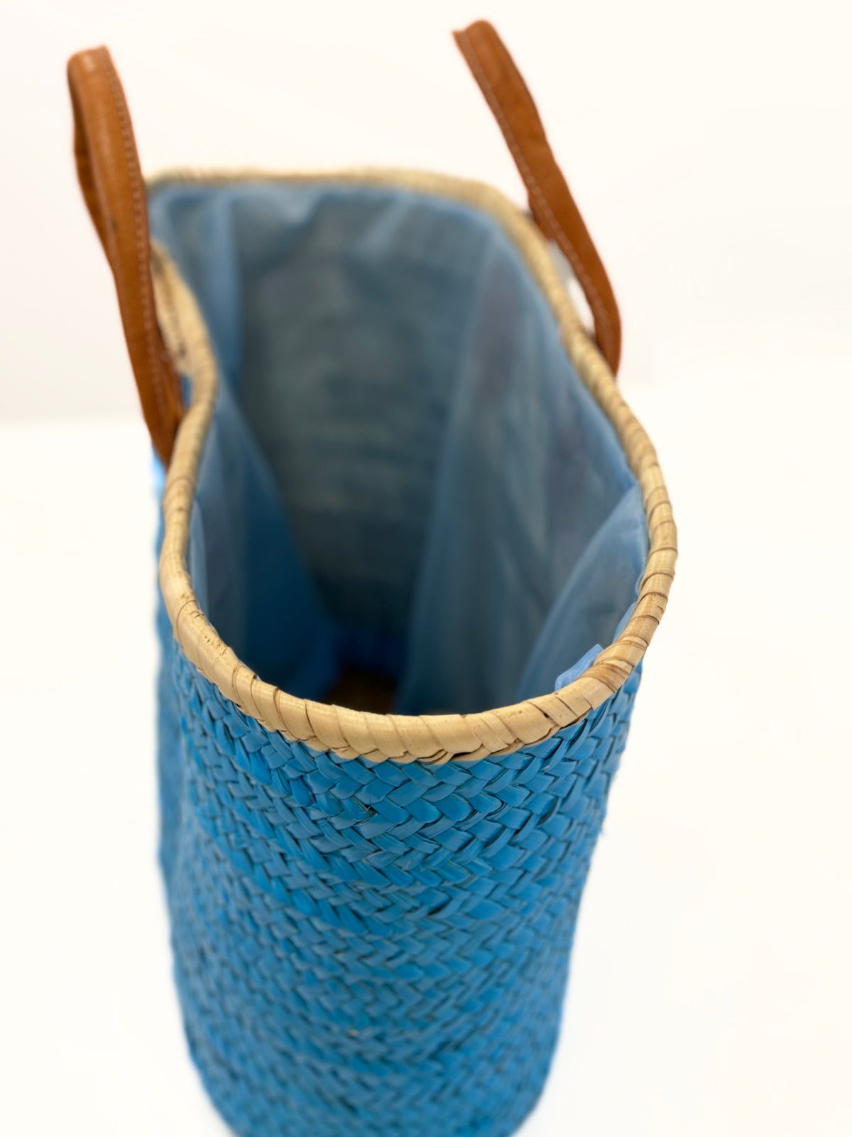 Turquoise handmade palm leaf basket with white sea star, side view showing blue fall-out inlet and drawstring on white background.