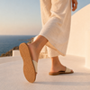 Woman walking in handmade VVC beige cowhide leather sandals, showing the textured anti-slip sole on a Greek island terrace in Crete.
