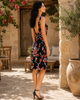 Side view of VVC black floral mini dress with deep open back, red and white flower design and flattering summer fit, made in Crete Greece