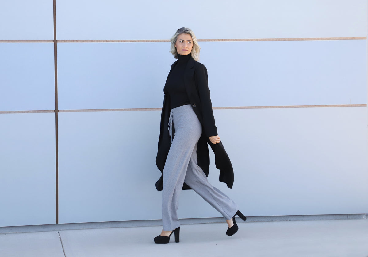 Full-length view of the VVC™ women’s black longline blazer worn with grey wide-leg trousers.