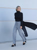 VVC™ black longline blazer shown open in motion with grey wide-leg trousers in Sitia, Crete.