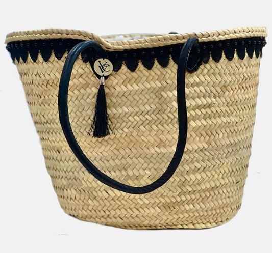 Front view of the VVC Black Pearl handmade palm-leaf beach basket with black lace trim and black handles.