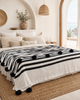Large VVC black and white pompom blanket made from 100% organic cotton, handmade in Morocco and styled as an elegant bed cover for modern interiors