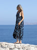 Woman walking beside the sea in the VVC blue-and-black floral sequin mullet dress, showing the movement of its flowing hem.