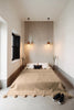 Front view of the VVC Café Latte organic cotton throw blanket showing its woven texture and decorative pompoms, 150 × 200 cm.