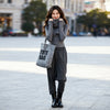 Full-length front view of a woman wearing VVC dark-grey striped harem trousers on a city street.