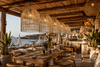 Natural raffia pendant lampshades in a wood and bamboo boho beach club restaurant overlooking the sea in Crete.