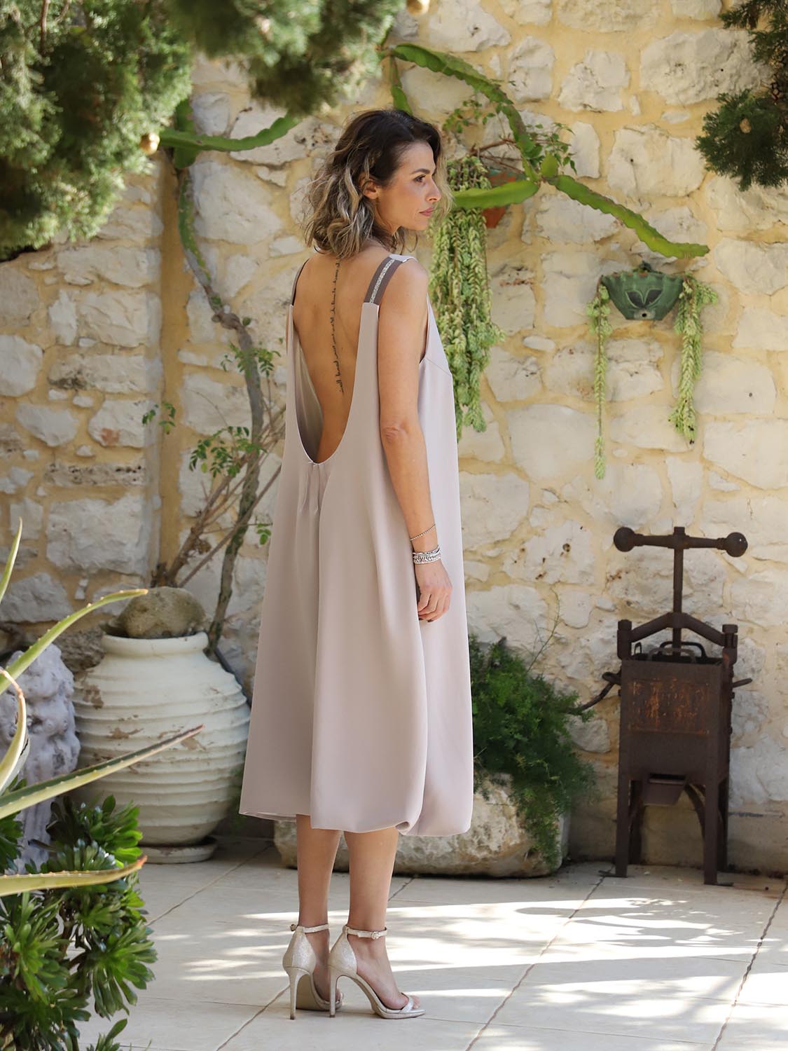 Back view of the VVC Flowing Blush Low-Back Midi Dress showing the deep scoop back, metallic shoulder straps and flowing A-line silhouette, made in Greece.