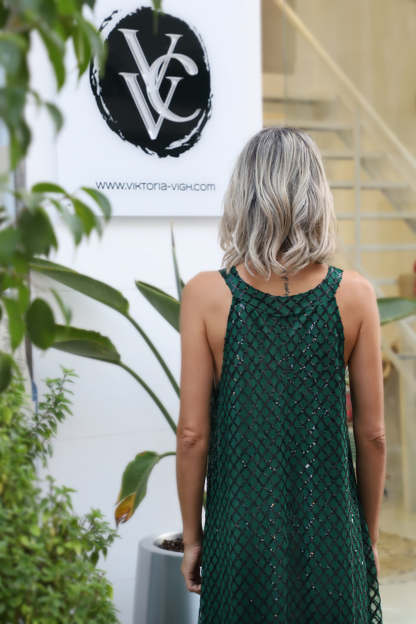 Rear angle showing longer back hem and elegant drape of VVC™ green sequin maxi dress, made in Greece.