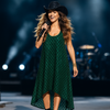 Model performing live on stage wearing VVC green sequin maxi dress with black crystal cowboy hat. Stylish and glamorous evening look for summer events.