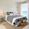 Handmade Moroccan cotton blanket by VVC with black woven stripes and off-white organic cotton, styled in a bright Mediterranean bedroom interior