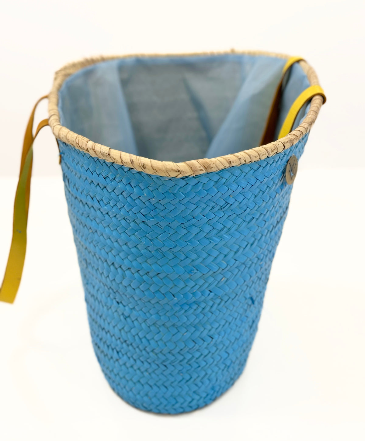 Side view of handmade turquoise palm leaf basket with yellow handles and sea star motif, designed for comfortable shoulder carrying.