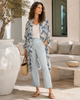 Woman wearing VVC Italian silk kimono with blue floral print, light blue trousers and white top, styled as elegant resort wear in Sitia, Crete