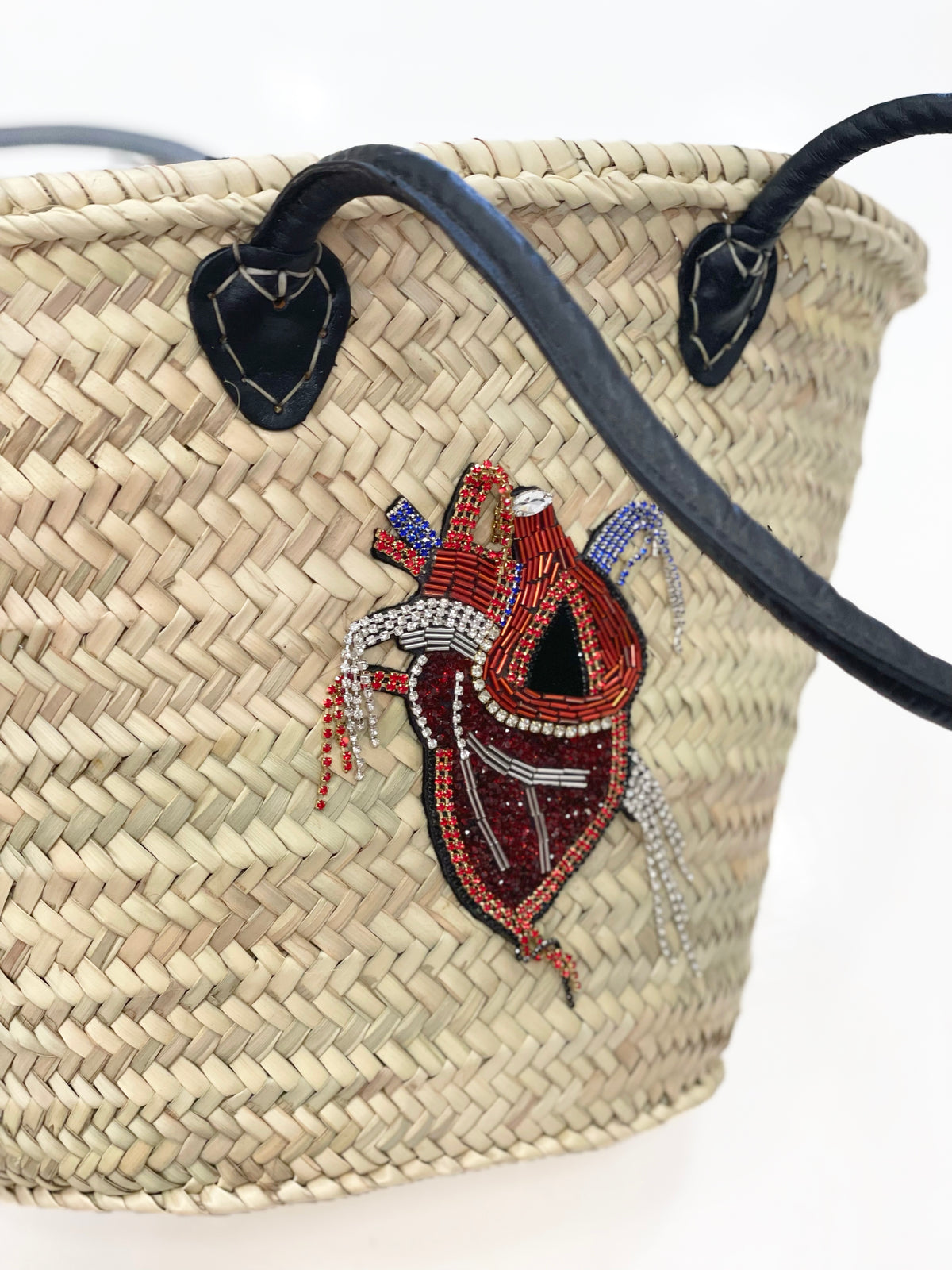 Close-up of the handmade rhinestone and pearl Kardia Heart applique on a VVC™ raffia basket. Artisan beadwork inspired by anatomy, craftsmanship and contemporary boho luxury design.