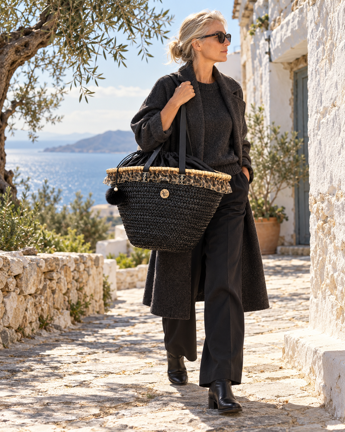 Woman carrying VVC™ large black raffia basket bag with leopard-print lining in Crete, Greece