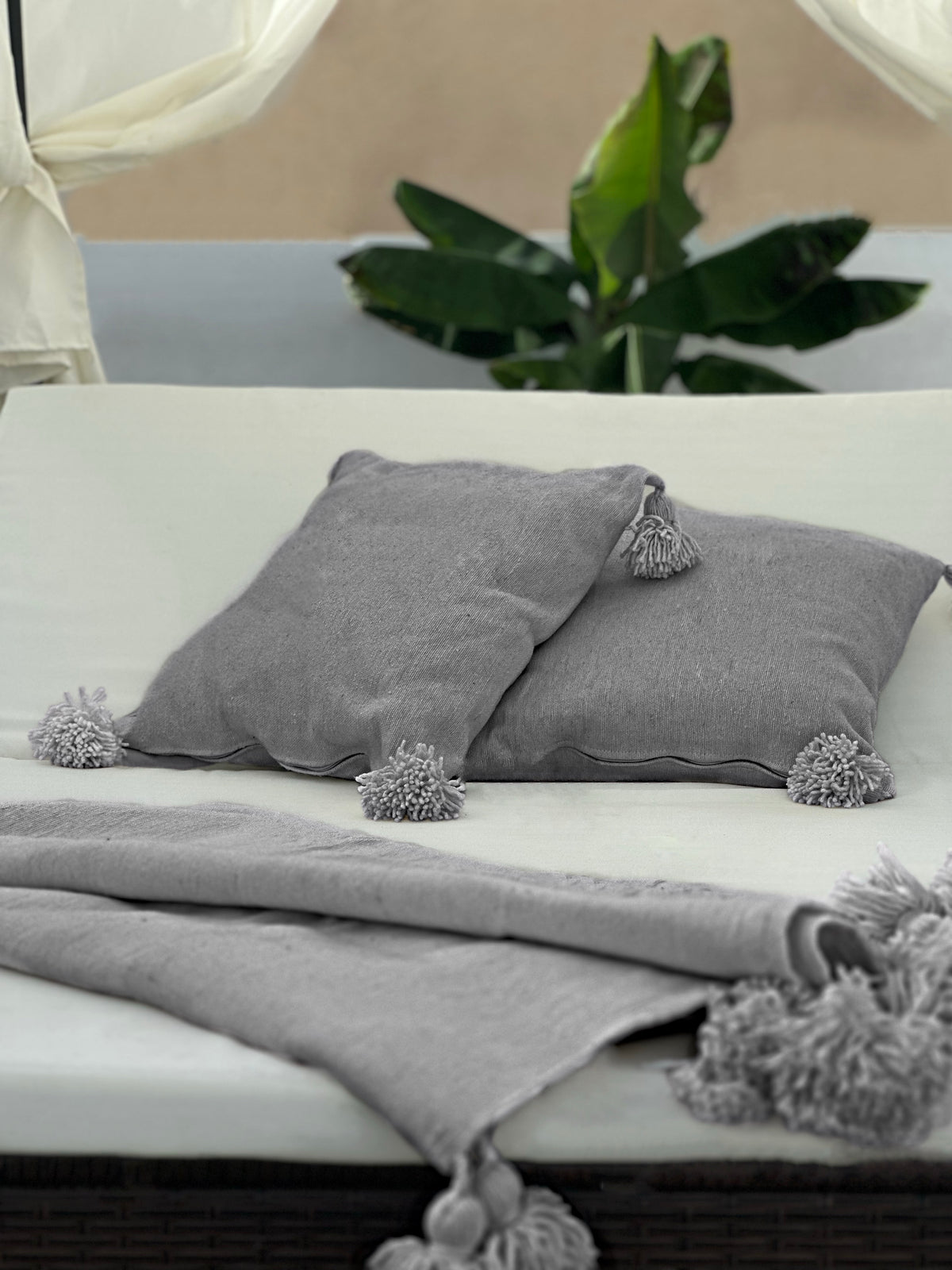 Dark gray organic cotton blanket by VVC™ styled in modern outdoor bed, made in Morocco.
