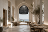 XXXL black woven pendant lampshade in a minimalist Greek island hotel restaurant hall with high ceiling and sea view in Crete.