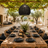 XXXL black handmade bast-fibre pendant lampshade casting romantic woven light shadows in a high-ceiling minimalist Greek island living room in Crete.