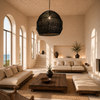 XXXL black handmade bast-fibre pendant lampshade casting woven light patterns in a bright Greek island living room with arched windows and sea views, styled for VVC SHOP Sitia.