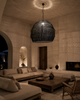 XXXL black handmade bast-fibre pendant lampshade creating romantic woven light shadows in a high-ceiling minimalist Greek island living room in Crete.