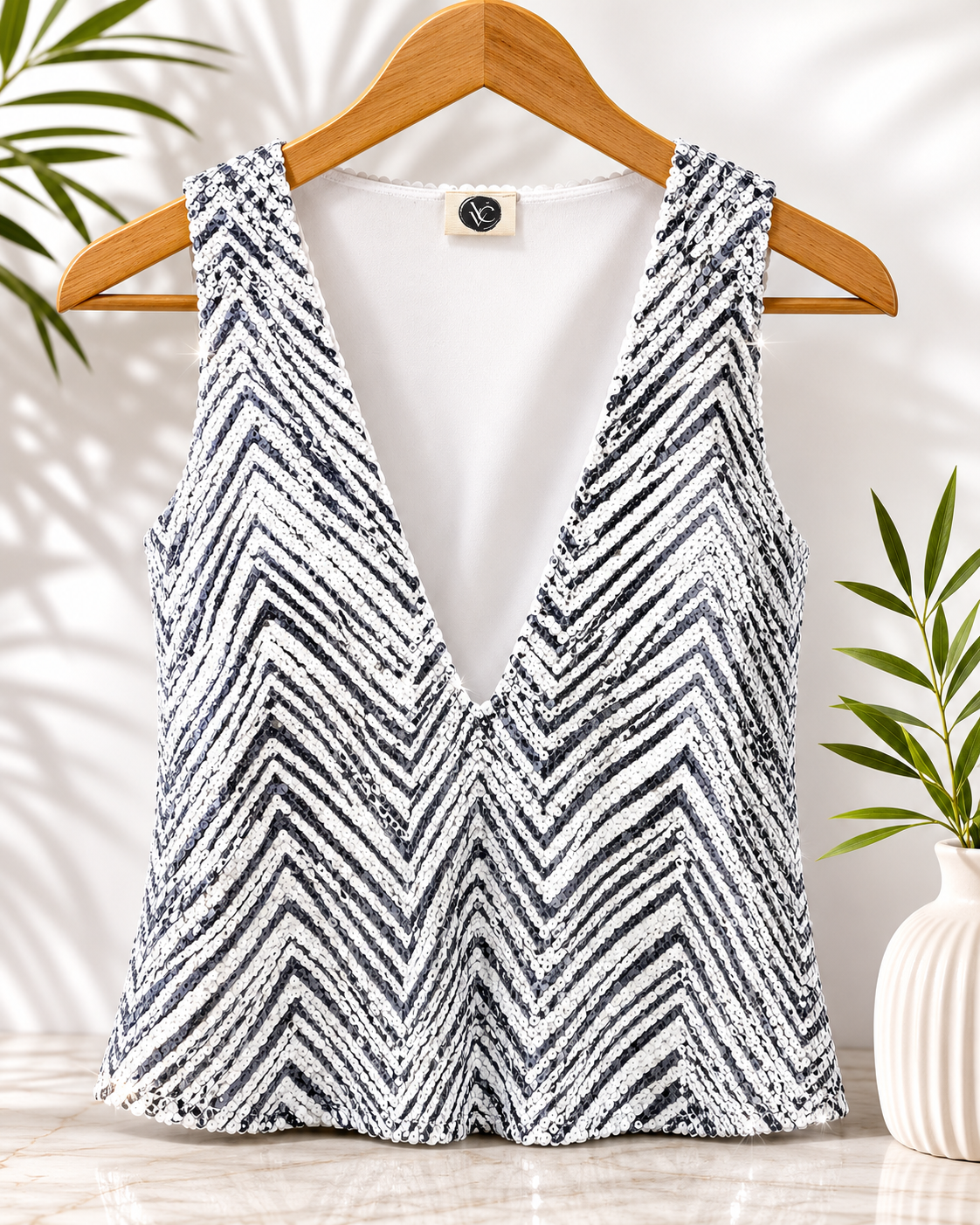 Black and white zigzag patterned sleeveless top on a wooden hanger with a neutral background VVC Sitia.