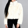 Close-up of a white cropped faux fur jacket on a white studio background, highlighting the soft texture and detailed faux fur finish.